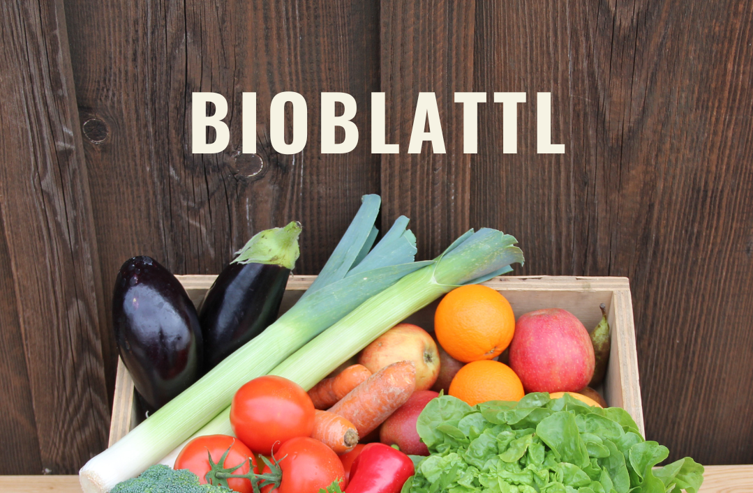 KI generiert: Das Bild zeigt eine Holzkiste mit einer Vielfalt an frischem, buntem Obst und Gemüse, darunter Salat, Brokkoli, Tomaten, Orangen und Lauch. Oberhalb der Kiste steht der Schriftzug "Bioblattl".