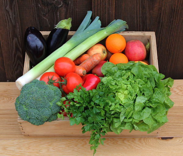 KI generiert: Eine Kiste voller frischem Gemüse und Obst auf einem Holztisch.