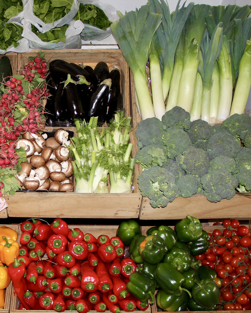 KI generiert: Verschiedene frische Gemüsearten, wie Auberginen, Lauch, Paprika und Brokkoli, in Holzkisten ausgestellt.